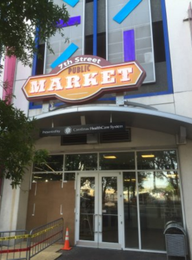 This image shows that shoppers are browsing fresh produce and handmade goods at The Market at 7th Street in Charlotte, supporting local farmers and artisans while enjoying a lively marketplace atmosphere.