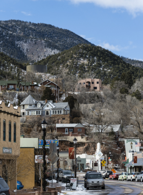 This image shows a natural mineral spring in Manitou Springs, with people filling their bottles from the bubbling waters surrounded by lush greenery.