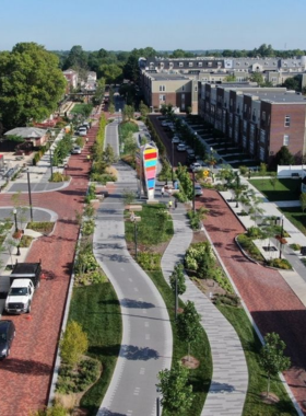 "This image shows a lively street in Broad Ripple Village, with colorful murals, cafes, and shops along the bustling sidewalk."