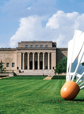 "This image shows the grand exterior of the Nelson-Atkins Museum of Art, featuring its large columns and expansive lawn with the famous shuttlecock sculptures in the foreground."