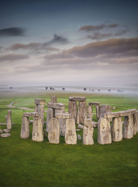 This image shows the mysterious ancient stone circle of Stonehenge in a green, open landscape.