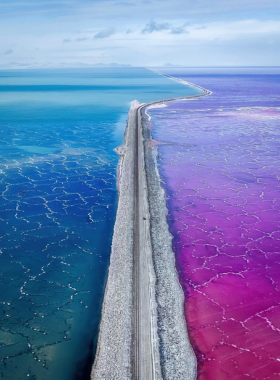 "This image shows that the Great Salt Lake reflects the colors of a stunning sunset, with calm water and mountains in the distance."