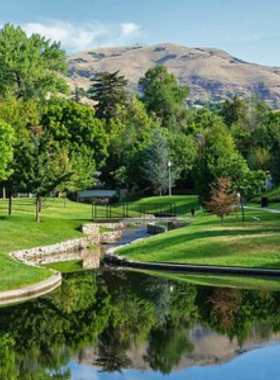 This image shows that Liberty Park has a peaceful lake with a fountain and shaded walking paths surrounded by greenery."