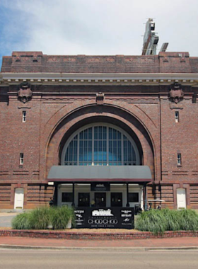 This image shows the historic Chattanooga Choo Choo train station, now a hotel and entertainment center. Visitors can see vintage train cars, landscaped gardens, and nearby dining areas.