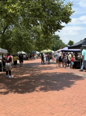 This image shows the Chattanooga Market, with outdoor stalls displaying fresh produce, crafts, and artisan goods. Visitors are browsing, enjoying local foods, and supporting community vendors.