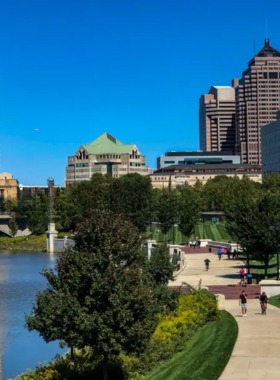 "This image shows the Scioto Mile in Columbus, Ohio, with scenic riverfront pathways, green lawns, and the city skyline in the background, where visitors enjoy peaceful walks, fountains, and community events."