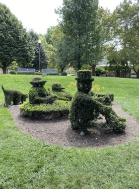 "This image shows Topiary Park in Columbus, Ohio, where trees and bushes are artfully sculpted into figures from the famous painting 'A Sunday Afternoon on the Island of La Grande Jatte,' creating a unique garden scene."