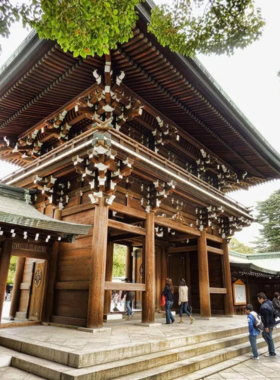 This image shows the Meiji Shrine in Tokyo, a tranquil Shinto shrine dedicated to Emperor Meiji and Empress Shoken. Visitors are seen performing traditional rituals, such as washing hands at the purification fountain before entering the shrine to offer prayers and reflections.