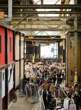 This image shows the vibrant atmosphere of the IJ Hallen Flea Market in Amsterdam, with hundreds of stalls offering vintage goods, antiques, and local crafts.