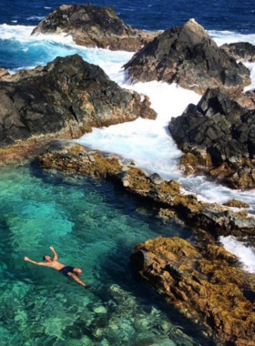 This image shows that Aruba’s Natural Pool, or Conchi, is a unique geological formation, where visitors can swim in calm waters surrounded by volcanic rock formations, creating a tranquil experience.