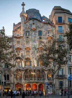 This image shows Casa Batlló, a colorful and whimsical building designed by Gaudí in Barcelona, with its unique undulating facade and striking ceramic tiles.