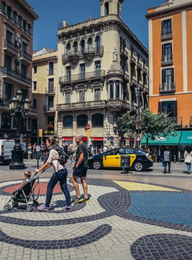 This image shows Las Ramblas, a lively street in Barcelona, lined with trees, shops, and cafes, full of tourists and street performers enjoying the vibrant atmosphere.