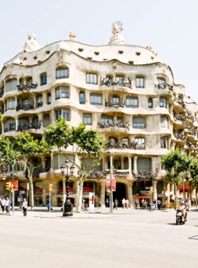 This image shows Casa Milà, also known as La Pedrera, a unique building designed by Antoni Gaudí in Barcelona, with its wavy stone facade and unusual rooftop sculptures.