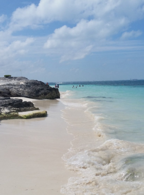 This image shows visitors enjoying water sports at Playa Tortuga in Cancún, where people participate in jet skiing, parasailing, and other exciting water activities