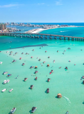 This image shows a lively scene at Crab Island with floating vendors, colorful inflatables, and people enjoying the shallow turquoise waters under the sun.