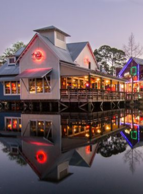 This image shows the lively Village of Baytowne Wharf at night, with lit-up buildings, bustling streets, and families enjoying various attractions.