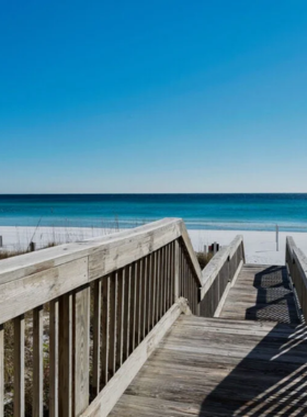 This image shows a peaceful scene at Crystal Beach Park with soft sands, tranquil waves, and people unwinding under colorful beach chairs and umbrellas.

