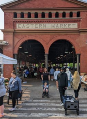 This image shows the colorful stalls and bustling atmosphere of Eastern Market, with fresh produce and artisan goods on display.