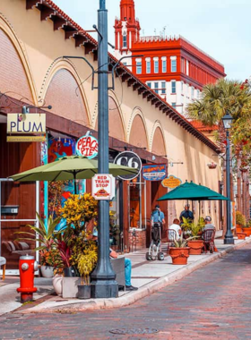  "This image shows the historic district of St. Augustine, with cobblestone streets, colonial-style buildings, and tourists walking past landmarks like the Castillo de San Marcos."