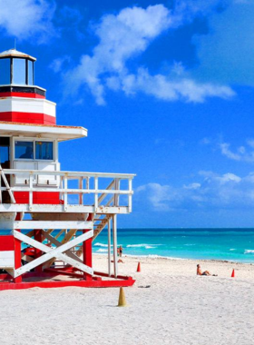  "This image shows the vibrant South Beach in Miami, with its golden sand, clear blue waters, and stylish beachgoers enjoying the sunny day by the iconic Art Deco buildings."