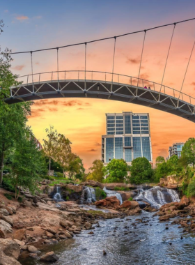  This image shows the scenic waterfalls at Falls Park on the Reedy, surrounded by lush greenery and the iconic Liberty Bridge, offering a peaceful and picturesque setting for visitors in downtown Greenville.