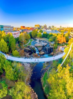 This image shows the Liberty Bridge overlooking the waterfalls at Falls Park. The modern design of the bridge and the natural beauty of the falls make it a standout landmark in Greenville.