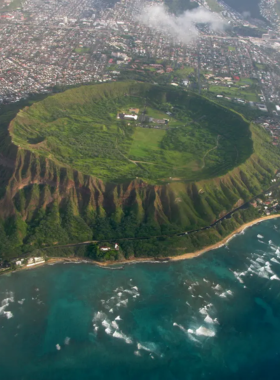 This image shows hikers climbing the famous Diamond Head Trail, surrounded by lush greenery and rocky terrain. The steep ascent leads to a panoramic view of Waikiki and the Pacific Ocean at the summit.