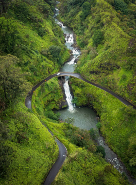  This image shows the scenic Road to Hana with lush greenery, waterfalls, and the winding road surrounded by Maui's natural beauty.