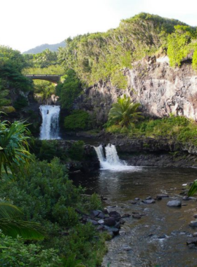 This image shows the serene Seven Sacred Pools at 'Ohe’o Gulch, surrounded by greenery and cascading waterfalls in the background.