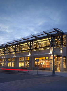 This image shows the bustling interior of the Milwaukee Public Market, filled with vendors selling fresh produce, seafood, and local food items, with shoppers browsing the stalls.
