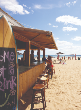 This image shows Bradford Beach during a sunny summer day, with people lounging on the sand, playing volleyball, and enjoying the beautiful view of Lake Michigan.