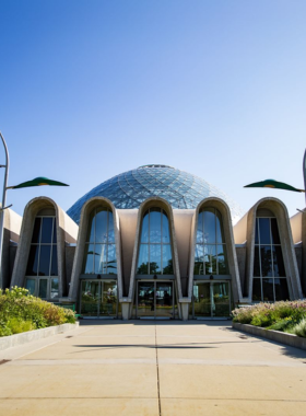 This image shows one of the domes of the Mitchell Park Horticultural Conservatory, filled with exotic plants and flowers, with visitors exploring the lush environment inside.
