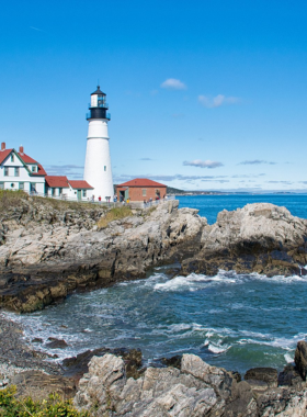 This image shows the Portland Head Light, Maine's oldest lighthouse, standing tall against the backdrop of the Atlantic Ocean with its white structure and scenic surroundings.
