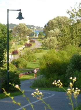  This image shows visitors walking along the scenic Eastern Promenade Trail, surrounded by green parks and offering views of the ocean and distant islands.