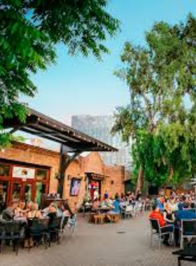 "This image shows San Pedro Square Market, a lively open-air market in San Jose, filled with food vendors offering a variety of cuisines, with visitors enjoying food, music, and a vibrant atmosphere."