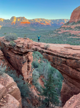 This image shows the famous Devil’s Bridge trail in Sedona, with hikers reaching the natural sandstone arch while enjoying panoramic views of the surrounding red rocks and desert landscape.