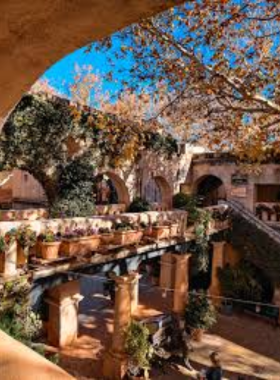 This image shows Tlaquepaque Arts and Shopping Village, a charming Sedona destination with cobblestone streets, colorful art galleries, and boutique shops set against a backdrop of red rock cliffs.