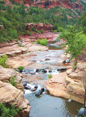 This image shows the fun-filled Slide Rock State Park, Sedona, with visitors sliding down natural water slides formed by Oak Creek and surrounded by stunning red rock scenery.