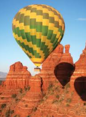  This image shows a serene hot air balloon ride over Sedona’s red rock landscape, providing passengers with an unforgettable aerial view of the natural beauty below during sunrise.