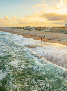 "This image shows St. Augustine Beach, offering four miles of white sand perfect for sunbathing, walking, and fishing. It’s a family-friendly beach with a splash pad for kids and beautiful views from the St. Johns County Ocean and Fishing Pier."