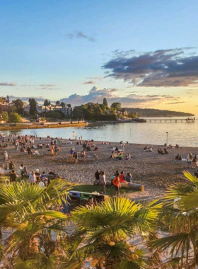 "This image shows the serene Kitsilano Beach in Vancouver, with people enjoying the sand, water, and views of the North Shore mountains on a sunny day."

