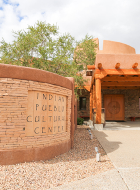 This image shows a traditional Pueblo dance performance at the Indian Pueblo Cultural Center, celebrating Native American culture.