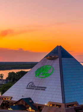 "This image shows the Bass Pro Shops at the Pyramid in Memphis, a unique entertainment complex with shopping, dining, bowling, and the tallest free-standing elevator in the U.S., offering stunning views of the Mississippi River."