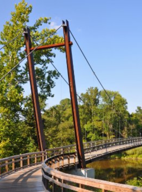 This image shows a cyclist riding along the scenic Neuse River Trail, surrounded by lush greenery, showcasing its tranquil and picturesque setting.