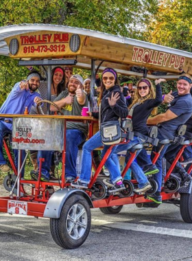 vThis image shows a lively group pedaling together on a Trolley Pub, enjoying music and drinks while exploring Raleigh’s downtown sights.