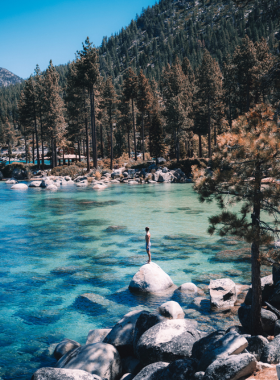 This image shows the breathtaking panoramic view of Lake Tahoe with its clear, turquoise waters and surrounding snow-capped mountains. Visitors enjoy activities like hiking, boating, and skiing, making it a year-round destination for outdoor enthusiasts.