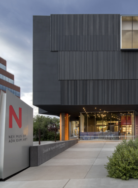 This image shows an art gallery at the Nevada Museum of Art in Reno, showcasing contemporary works from various artists. The museum’s stunning architecture, with its beautiful views of the Sierra Nevada Mountains, provides an immersive space for exploring diverse art forms and exhibits.