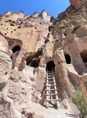 This image shows ancient cliff dwellings at Bandelier National Monument, with stunning views of the surrounding desert landscape and Ancestral Puebloan ruins.