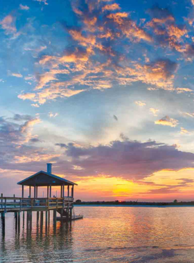 This image shows the peaceful Wrightsville Beach, with soft golden sands, clear blue waters, and people relaxing by the ocean, perfect for a calm beach getaway in Wilmington.