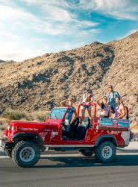 This image shows a red jeep on a thrilling desert tour through rocky terrain, with a guide sharing insights about the Coachella Valley’s unique desert landscapes and history.